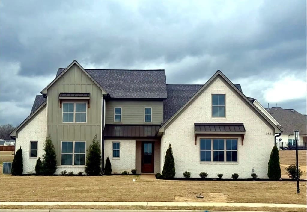 Cream brick and sage board-and-batten custom home exterior by M & D Custom Homes